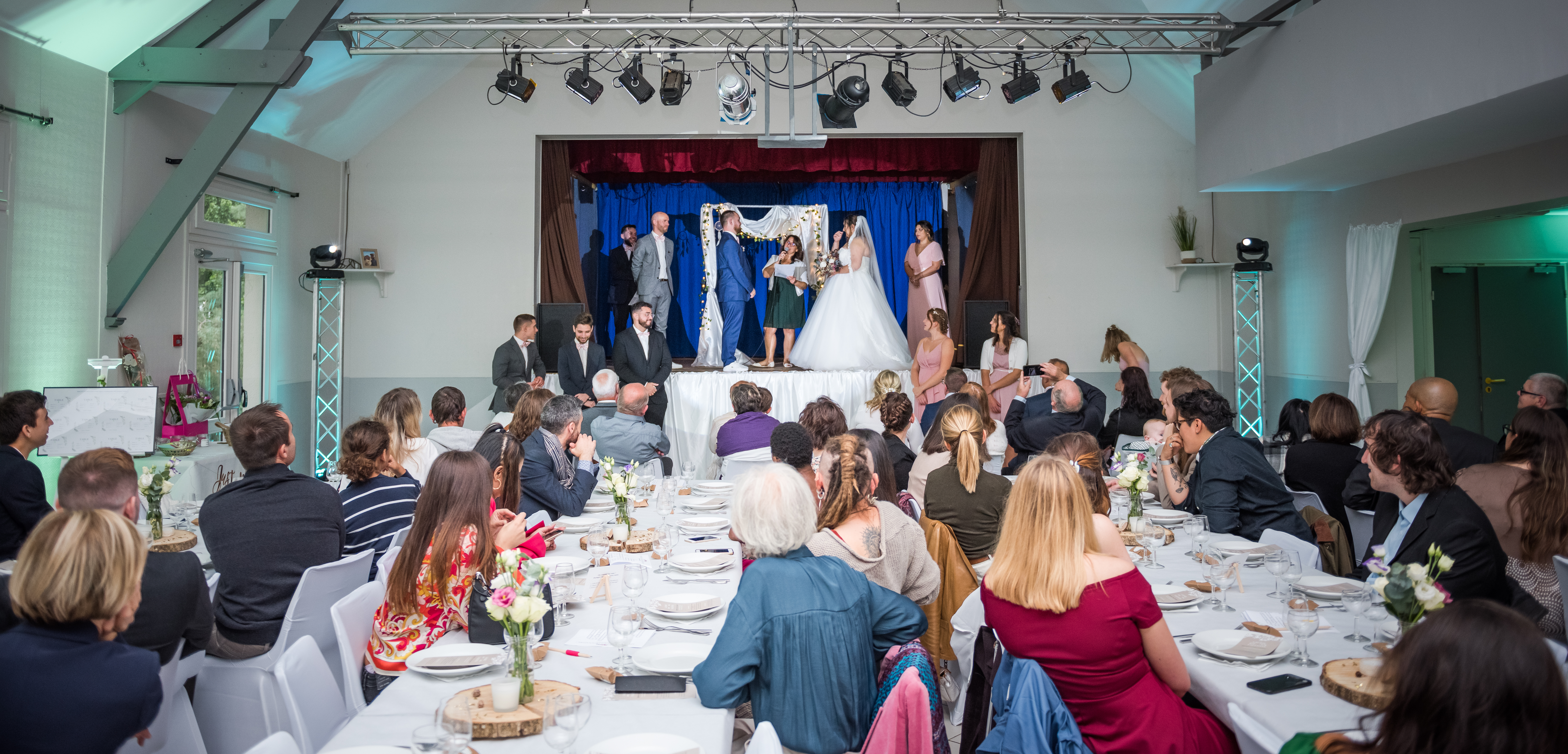 Mariage de Laurie et Valentin cérémonie laïque, les mariés se tiennent face à face sur une estrade face à tous leurs invités assis à des tables en ligne