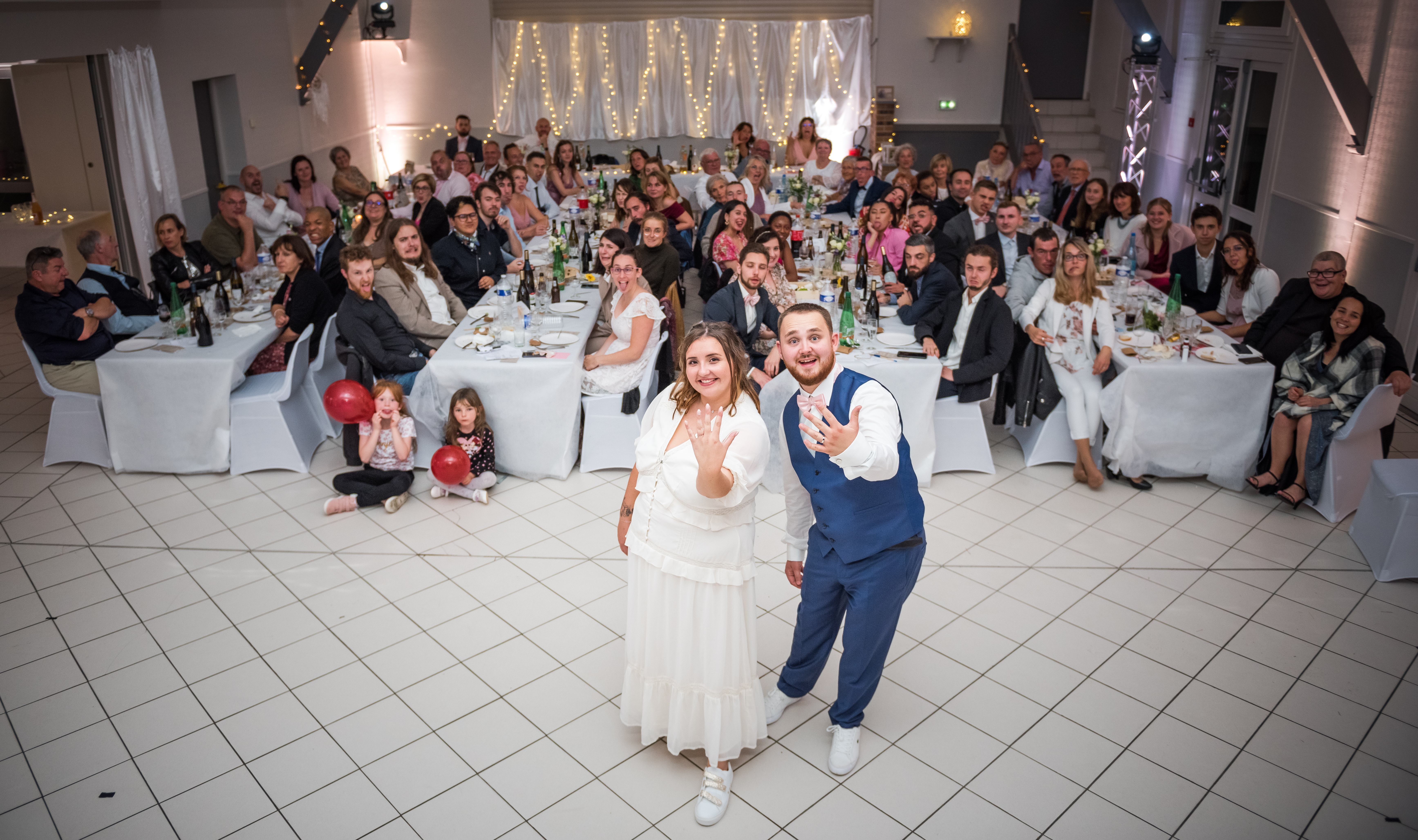 Mariage de Laurie et Valentin photo de groupe, les mariés montrent fièrement leurs alliances devant des invités qui font la grimace