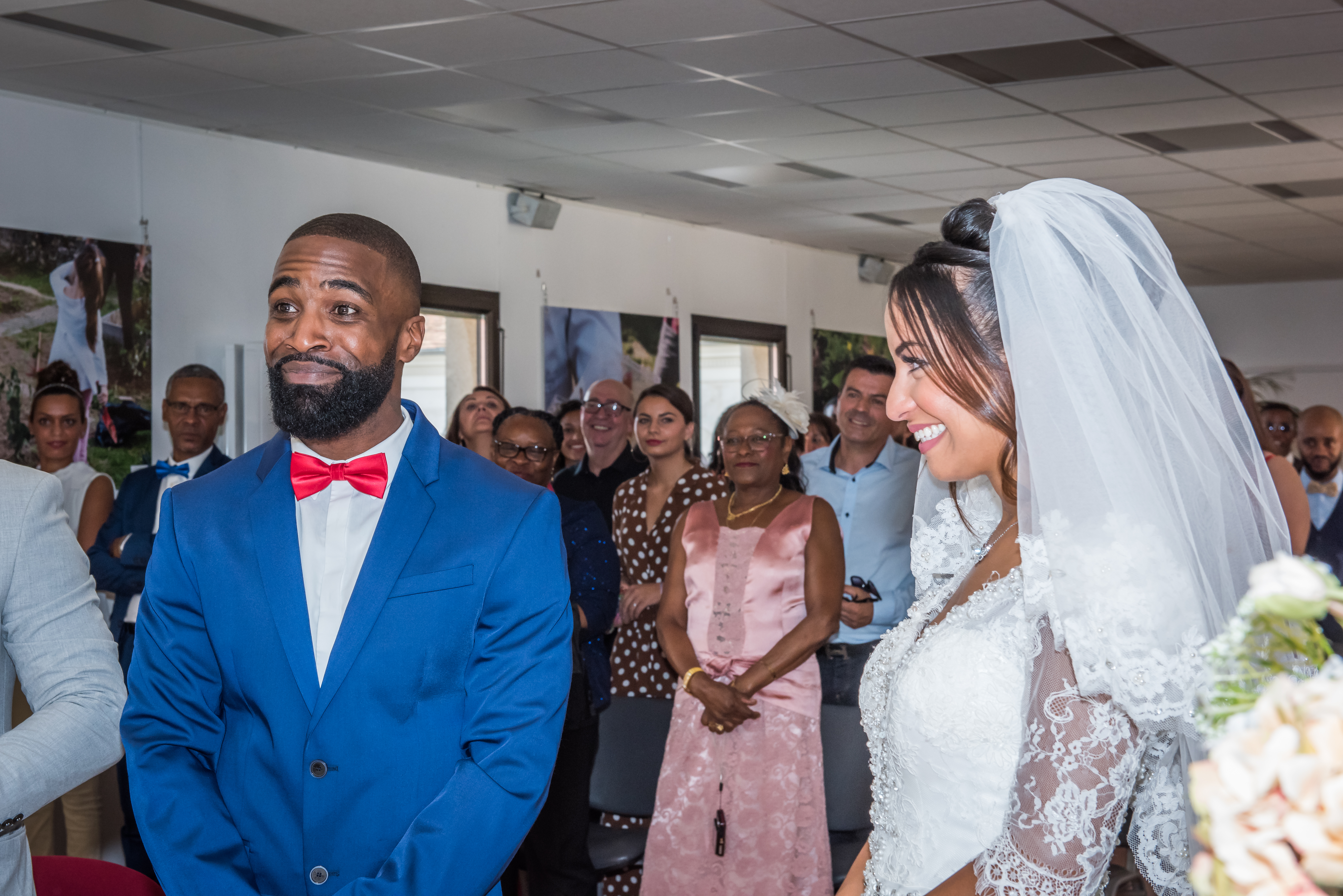 Mariage de Zara et Christy cérémonie, le marié, en costume bleu, et la mariée, en robe blanche, se disent oui devant leurs invités