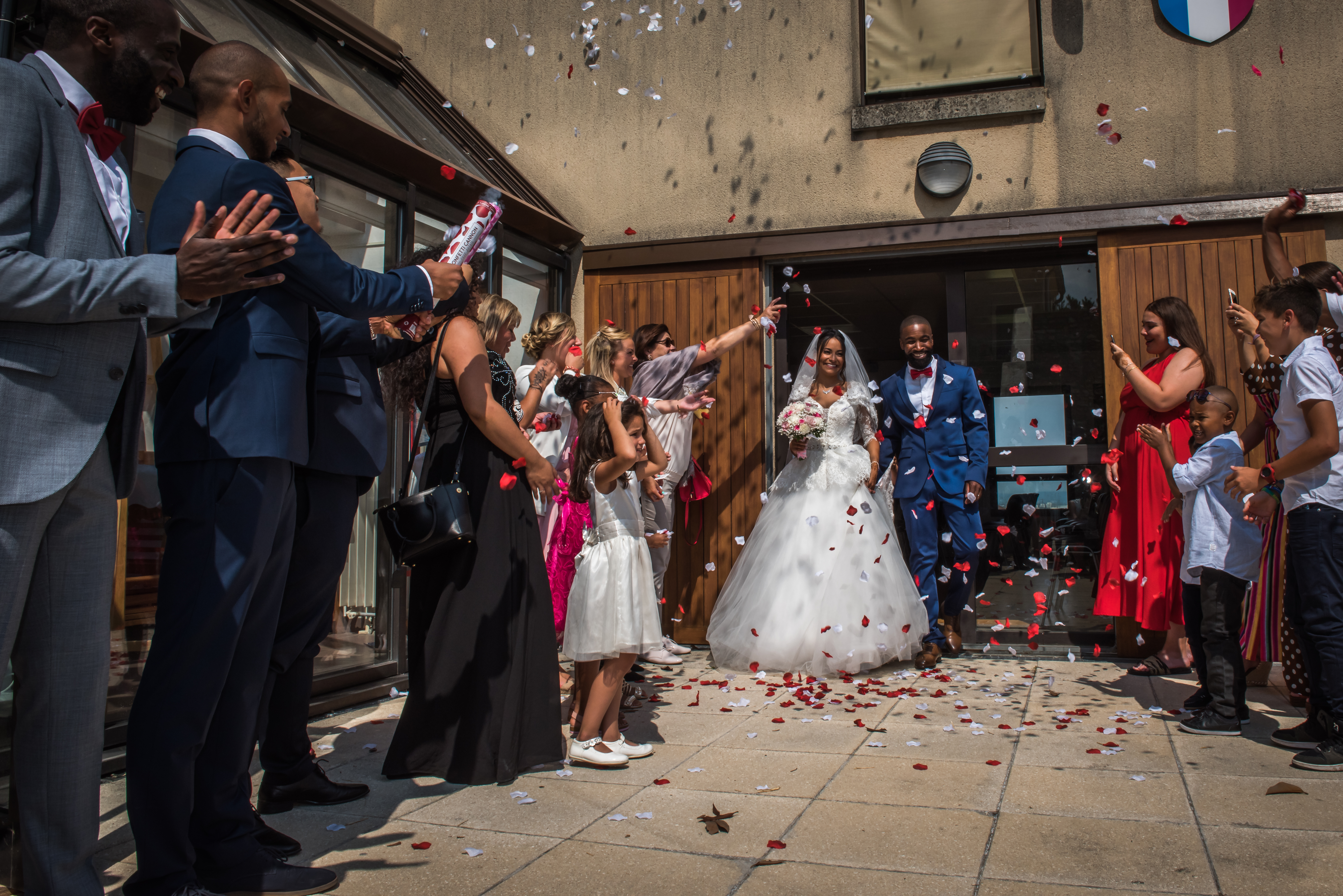 Mariage de Zara et Christy cérémonie sortie de la mairie, les mariés sont couvert de pétales de roses blanches et rouges