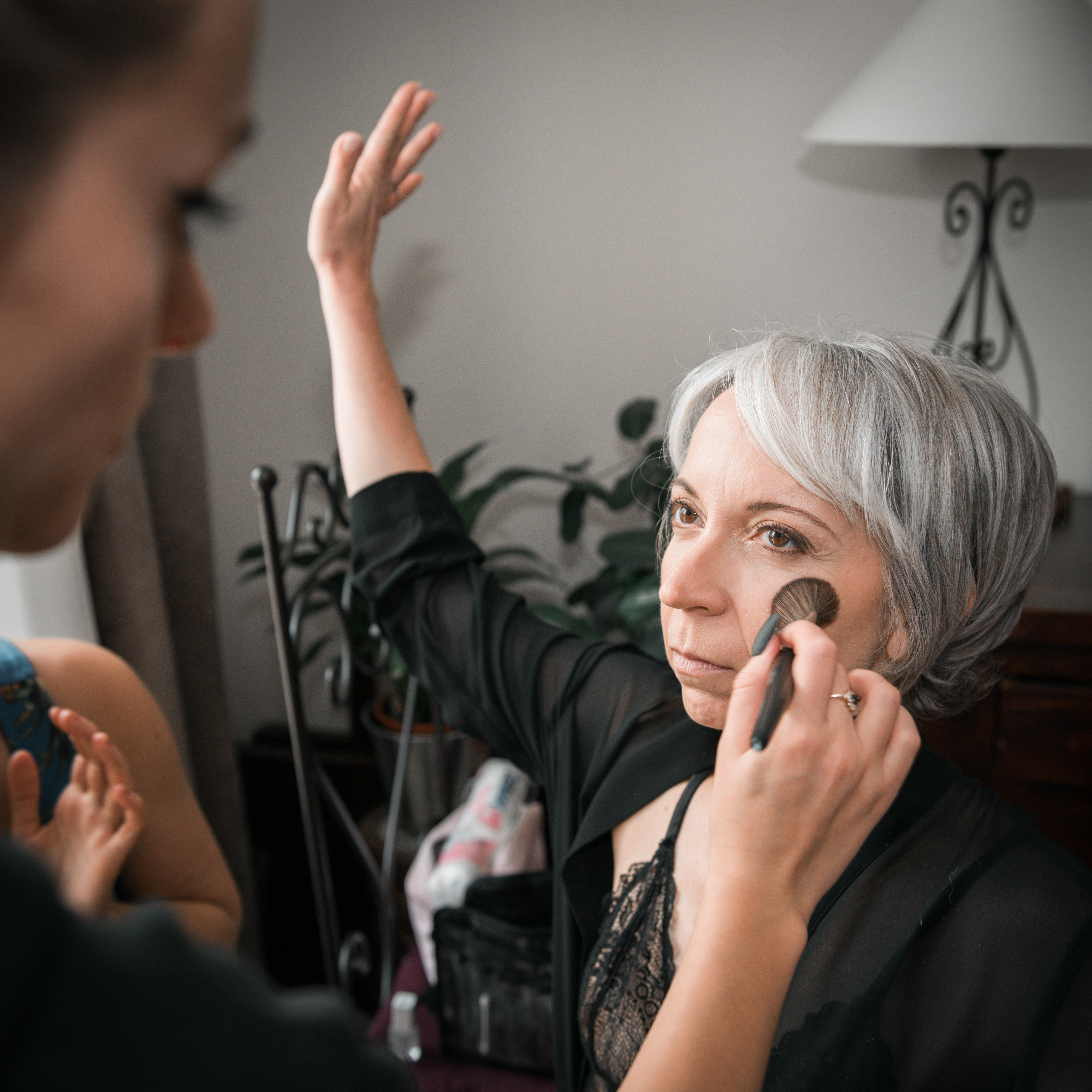 Mariage de Laurent et Valérie maquillage de la mariée, la mariée fait sécher son vernis pendant que la maquilleuse lui met de la poudre