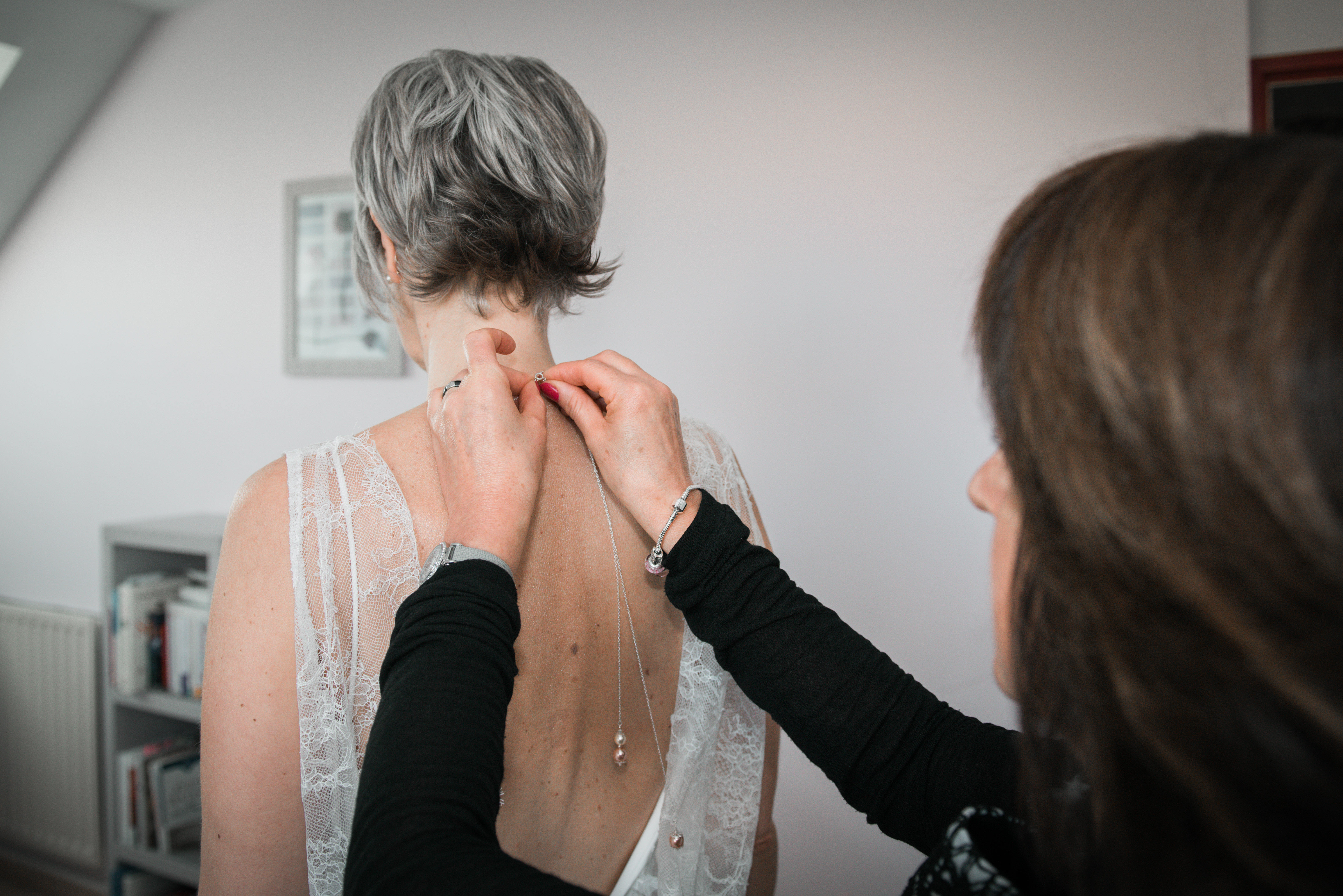 Mariage de Laurent et Valérie habillage de la mariée, une amie attache un collier de dos à la mariée